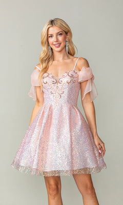 A woman wears the Shoulder-Bow Short Glitter Homecoming Dress 3363 in sparkly pink, featuring spaghetti straps, sheer off-the-shoulder sleeves, intricate bodice details, and a corset lace-up back against a plain background.