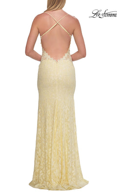 A woman wearing the Beaded Long Lace Prom Dress: La Femme 33647 in light yellow, featuring delicate lace detailing and a low, open back with strappy crisscross straps, viewed from behind.