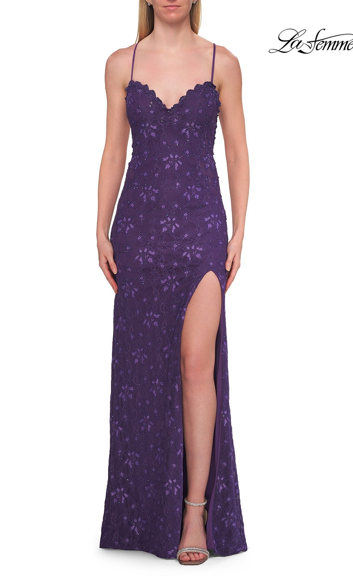A woman wearing the Beaded Long Lace Prom Dress La Femme 33647 in royal purple, featuring delicate lace details, spaghetti straps, a scalloped neckline, and a high side slit stands against a white background.