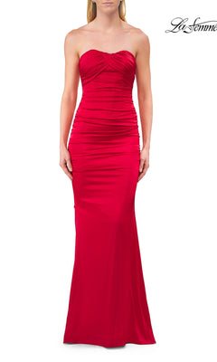 A woman models the La Femme 33654 Lace-Up Strapless Long Prom Dress in red, a body-contouring satin gown with ruched detailing that elegantly highlights her silhouette. She stands against a plain white background, showcasing the sophisticated evening look.
