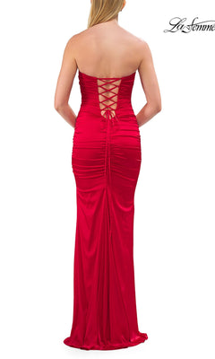 A woman stands facing away from the camera in the La Femme 33654 Lace-Up Strapless Long Prom Dress—a striking, floor-length red gown featuring a lace-up back and elegant ruched detailing.