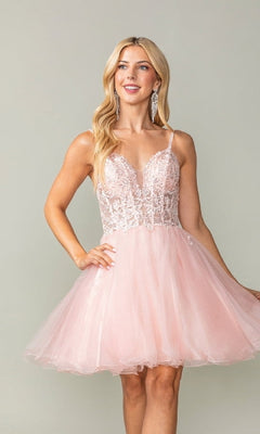 Woman wearing a pink short dress with a lace bodice and tulle a-line skirt against a plain background
