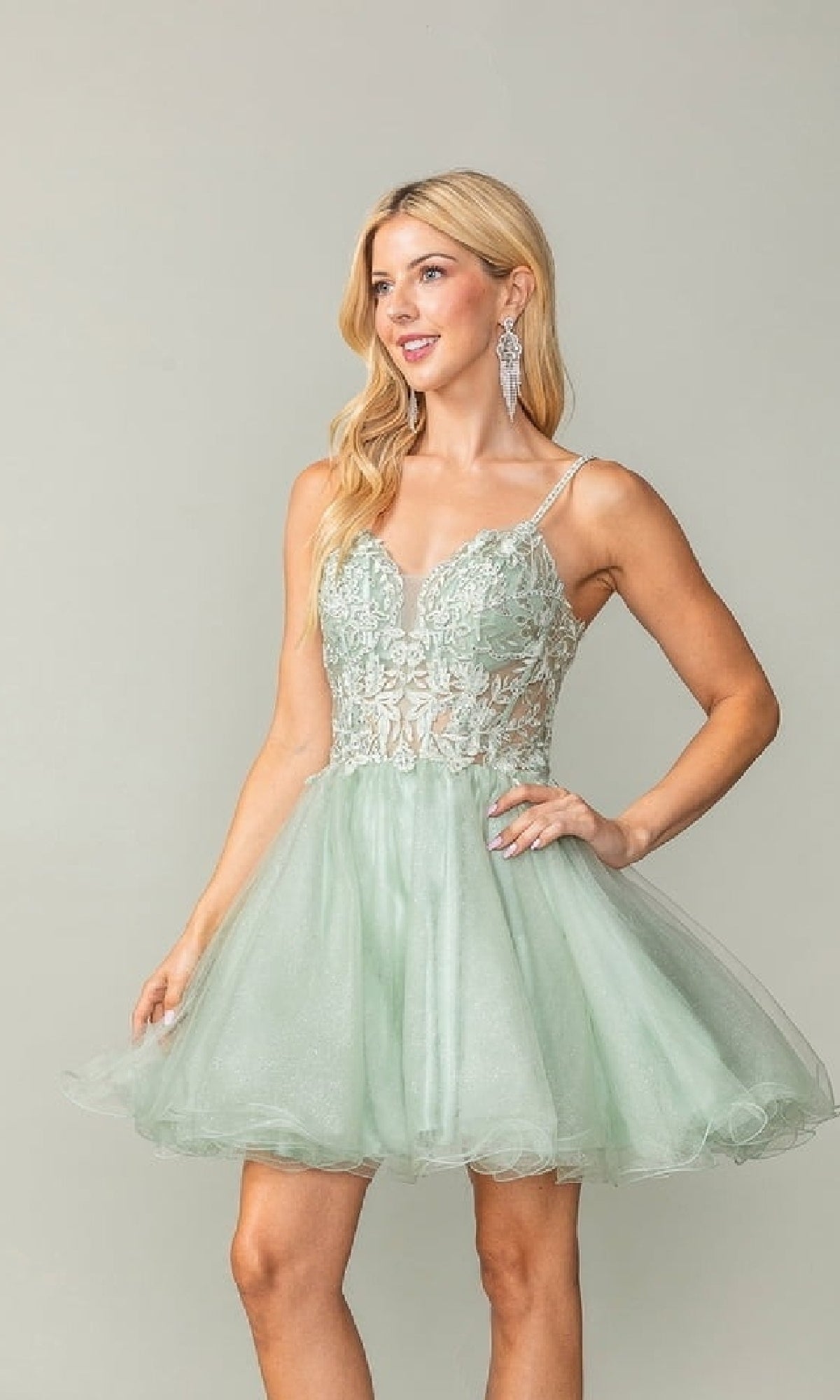 Woman wearing a light green dress with lace details on a plain background