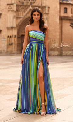 A woman stands outdoors in the La Femme 33690 multi-colored prom dress, featuring colorful vertical stripes, a strapless design, and a high leg slit, paired with white heels.