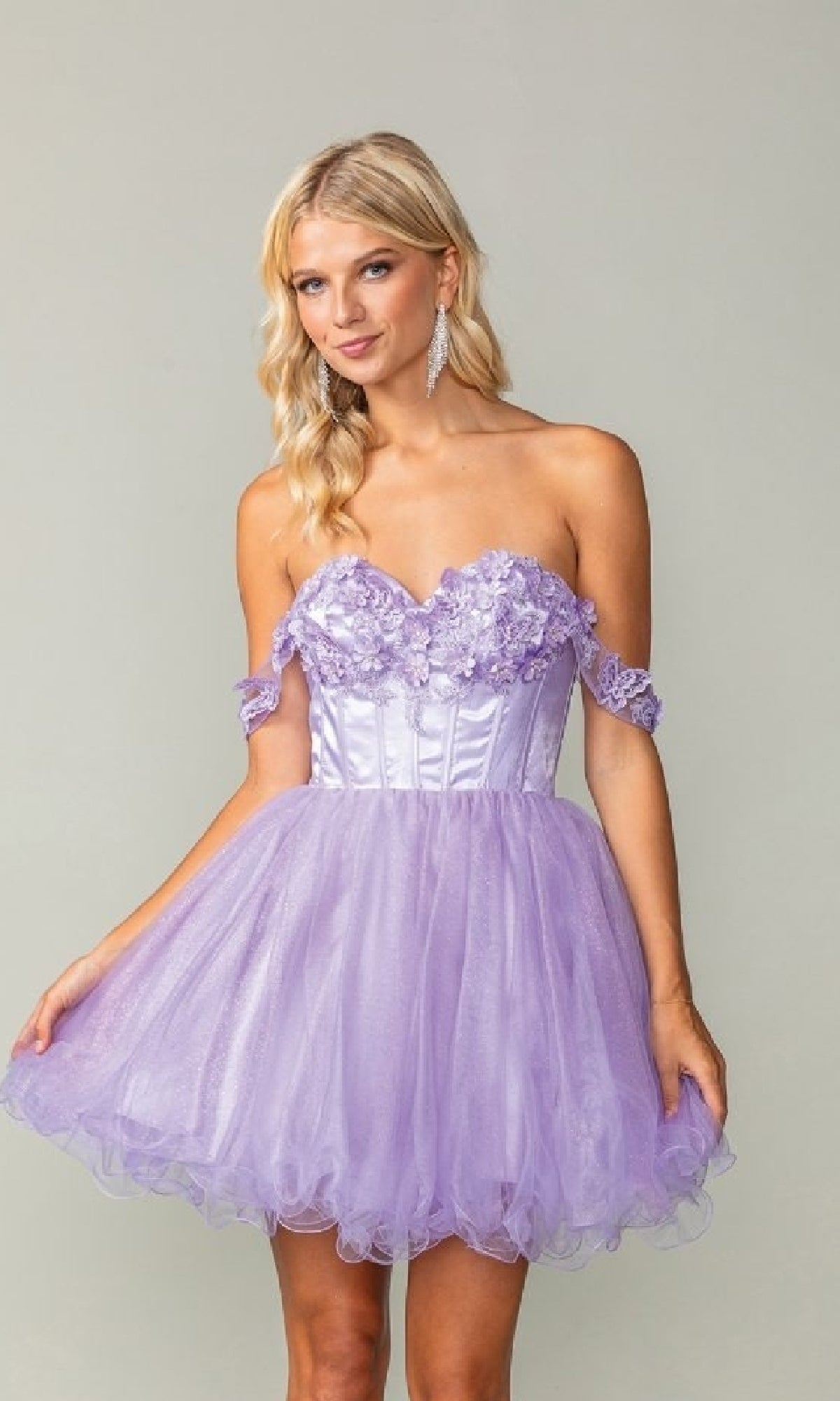 Woman wearing an off-shoulder lilac purple dress with floral embellishments on a plain background