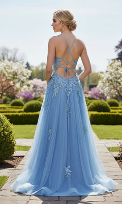 A woman stands outdoors among manicured hedges and blooming trees, wearing the La Femme 33716 lace-embroidered prom ball gown in long, light blue with a backless design.