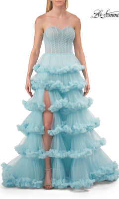 A woman wearing the Strapless Tiered Prom Ball Gown: La Femme 33717 in Cloud Blue—a ball gown with a corset-style bodice, sweetheart neckline, tiered skirt, and front slit—standing against a white background.