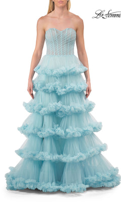 A woman wears the Strapless Tiered Prom Ball Gown: La Femme 33717, a light blue prom dress with a strapless sweetheart neckline, fitted bodice, and tiered full-length ball gown skirt.
