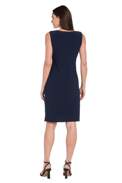 A woman stands facing away in the R&M Richards 3371 short navy jacket party dress, paired with black heeled sandals, against a white background.