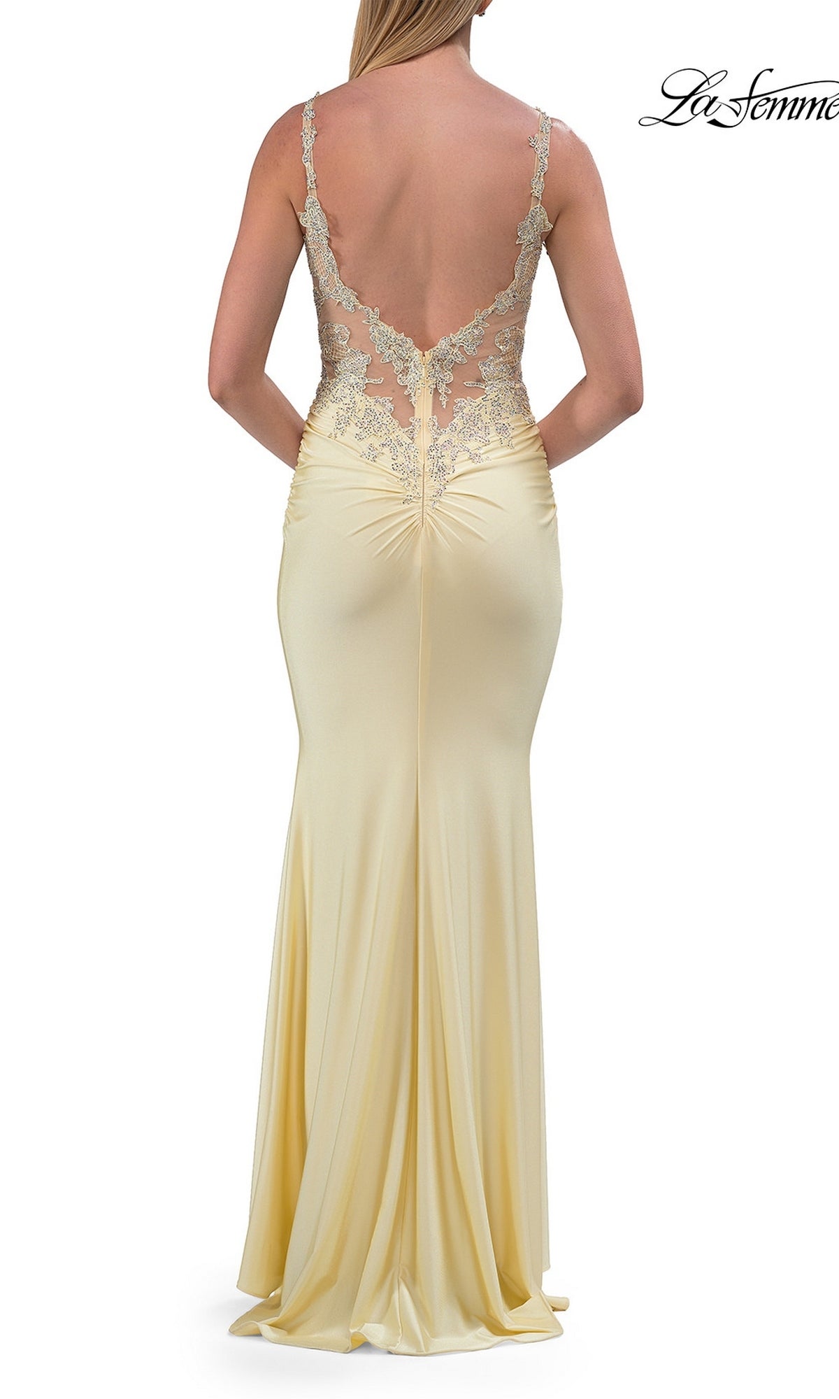 Woman in the Beaded-Bodice Long Prom Dress (La Femme 33731), a floor-length pale yellow gown showcasing an illusion-lace bodice with a sheer, embellished back and delicate lace details, standing facing away from the camera.
