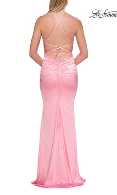 Wearing the La Femme 33735, a backless prom dress with lace trim, a woman showcases a light pink satin gown featuring crisscross straps, an open back, a fitted silhouette, and a floor-length hem.