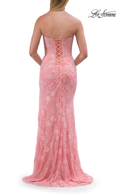 A woman stands with her back to the camera, showcasing the Strapless Long Lace Prom Dress: La Femme 33768. This elegant formal gown features a corset-style lace-up back and delicate floral lace in a soft peach hue, bringing classic beauty and timeless appeal to any special occasion.