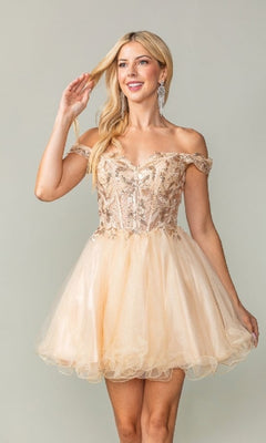 Woman wearing a short champagne colored short tulle dress against a plain background