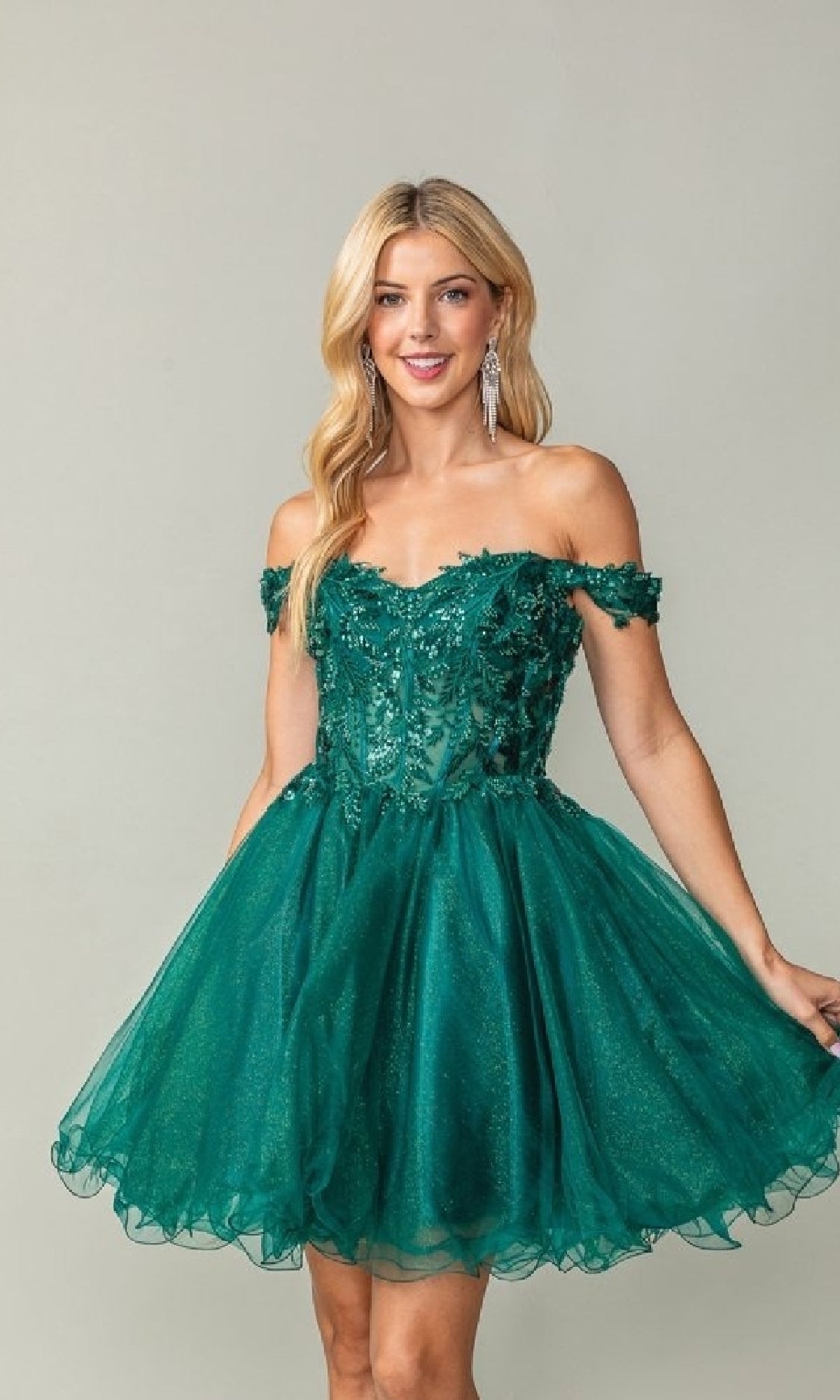 Woman wearing a short dark green off-shoulder dress against a plain background