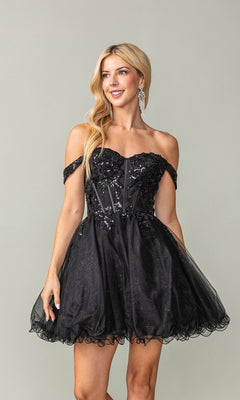 A woman stands against a plain background wearing the Short Corset Homecoming Dress: Dancing Queen 3383—a black, off-the-shoulder, short tulle dress featuring floral embellishments and a sparkly sheer corset bodice.