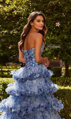 Woman wearing the La Femme 33855 long blue floral strapless ruffled prom dress stands in a garden, gazing over her shoulder at the camera.