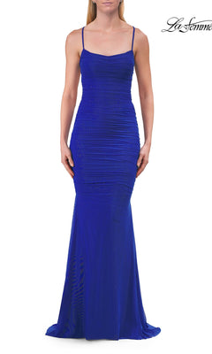 A woman wearing the Strappy Long Net-Jersey Prom Dress by La Femme (style 33857) in royal blue, featuring a fitted, floor-length silhouette with thin straps and subtle textured detailing, stands against a plain white background.