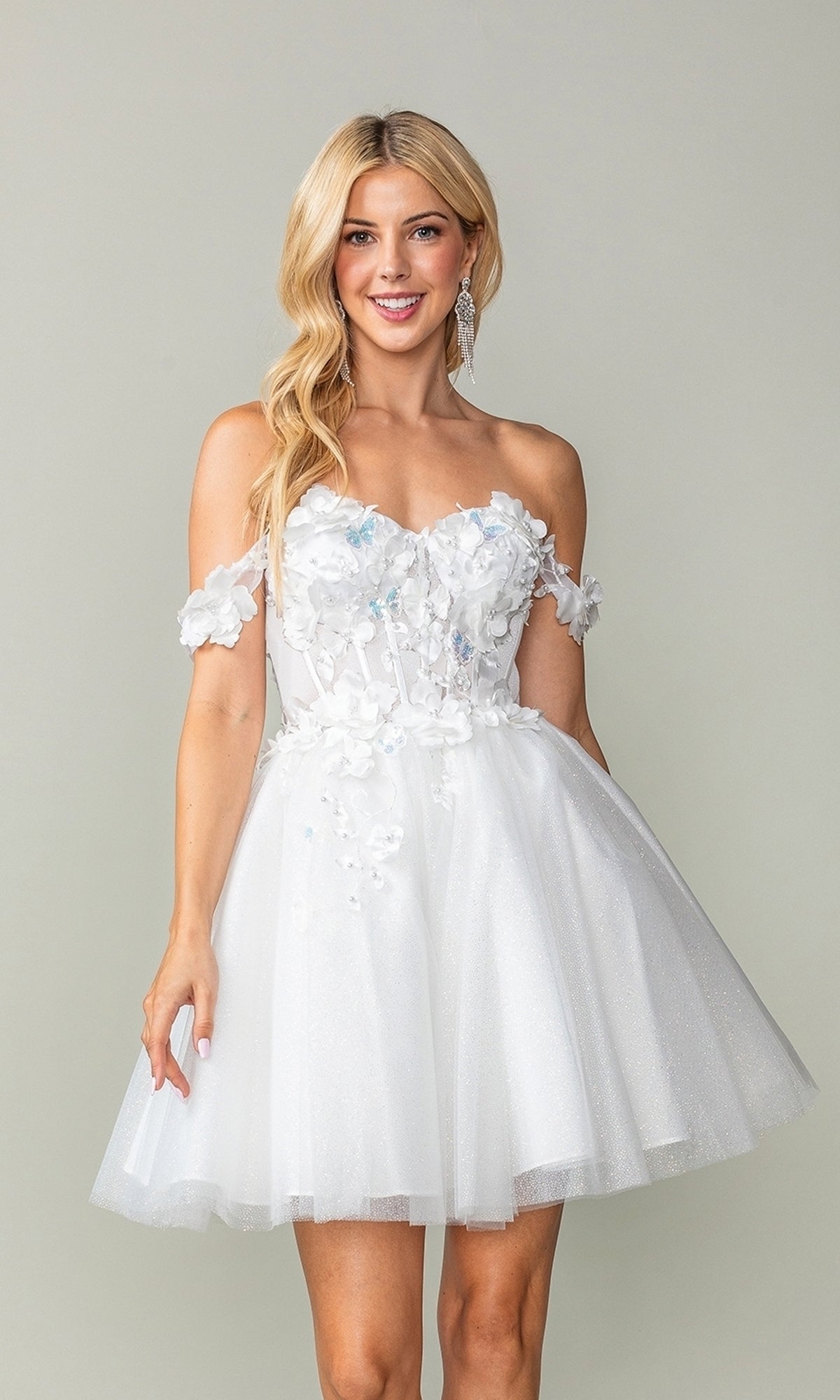 A woman models the Off-Shoulder Short Babydoll Homecoming Dress 3388, featuring floral appliqués and a flared tulle skirt—the ideal short cocktail dress for any special occasion.