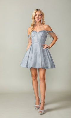 A woman wears the Fringed Off-Shoulder Short Homecoming Dress 3392—silver, short, with beaded fringe sleeves and a fitted corset bodice—paired with silver high heels, standing against a plain background.