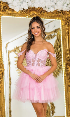 A woman stands before a gold-framed mirror, wearing the Dancing Queen 3402 short pink babydoll prom dress with floral lace details. White roses are visible above the mirror.