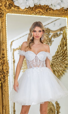 A woman stands before a large ornate gold mirror and golden angel wing decor, wearing the Ruffle Short A-Line Prom Dress: Dancing Queen 3406, a white off-shoulder dress with lace and tulle details.