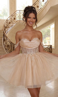 Woman in a strapless, champagne tulle short babydoll prom dress (Dancing Queen 3409) with lace details stands indoors by a decorative staircase, smiling—a chic and affordable choice for proms or any special occasion.
