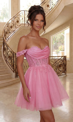 A woman in a pink, short babydoll prom dress (Dancing Queen 3409) stands indoors by a decorative staircase.