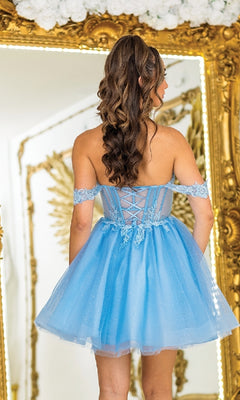 A woman with long, wavy brown hair wears the Dancing Queen 3409 short babydoll prom dress in blue as she stands facing a large ornate gold mirror.