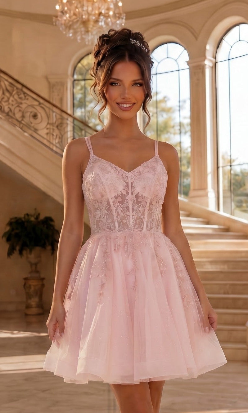 A woman in a blush, sleeveless Short Corset Prom Dress (Dancing Queen 3415) stands indoors before a grand staircase and large arched windows.