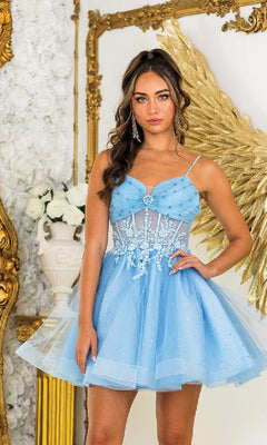 Woman wearing a light blue dress with floral embellishments in an elegant indoor setting.