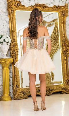 A woman in the Dancing Queen 3418 Off-Shoulder Short Prom Dress with a lace-up back stands by an ornate gold mirror and white floral decor, facing away to highlight this affordable prom dress’s elegant yet playful style.