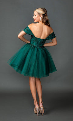 A woman wearing the Short Homecoming Dress: Dancing Queen 3433, which features an off-the-shoulder design, a short green glitter tulle skirt, and jeweled heels, stands with her back to the camera against a gray background.