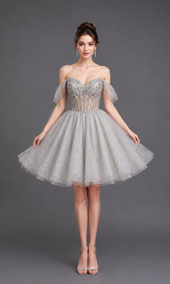 Wearing the Short Homecoming Dress: Dancing Queen 3438 in silver, a woman poses against a plain gray background. The strapless design features a fitted bodice and sparkly tulle skirt, accentuating her figure as shimmering details catch the light.
