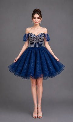 A woman stands against a gray background wearing the Short Homecoming Dress: Dancing Queen 3438 in navy—a dark blue, off-the-shoulder ball-gown featuring a flared, sparkly tulle skirt, sheer puff sleeves, elegant silver embellishments, and paired with silver high-heeled sandals.