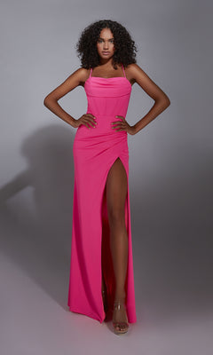 A woman stands with hands on hips against a gray background, wearing the Long Prom Dress: Aerie Couture 343—a bright pink, sleeveless gown featuring a corset bodice and a daring leg slit.
