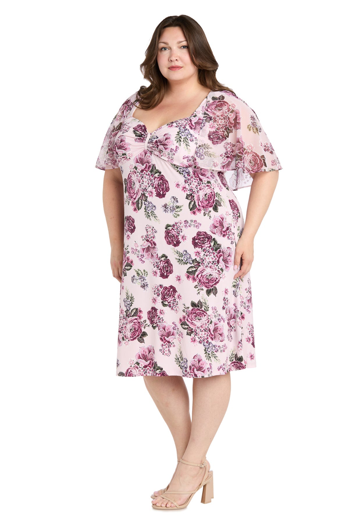 A woman wearing the R&M Richards 3467W plus-size pink party dress with sheer flutter sleeves and nude heeled sandals, standing against a white background.