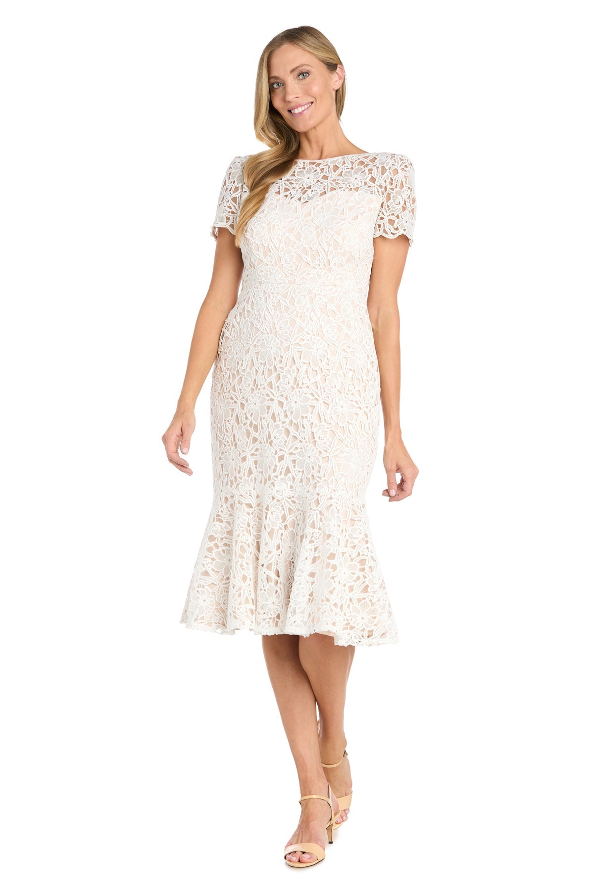 A woman smiles while standing in the R&M Richards 3498 Midi Lace Wedding Guest Dress, featuring short sleeves, white lace fabric, knee-length cut, and a flared hem.
