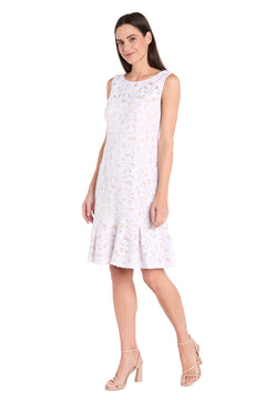 A woman wears the R&M Richards 3506P Petite White Lace Party Dress with a floral pattern and flared hem, paired with nude heeled sandals, standing against a white background.