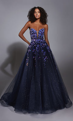 A woman models the Navy Blue Prom Ball Gown: Aerie Couture 350, with a strapless fitted bodice, deep neckline, floral embellishments, and an a-line glitter tulle skirt, set against a plain grey background.