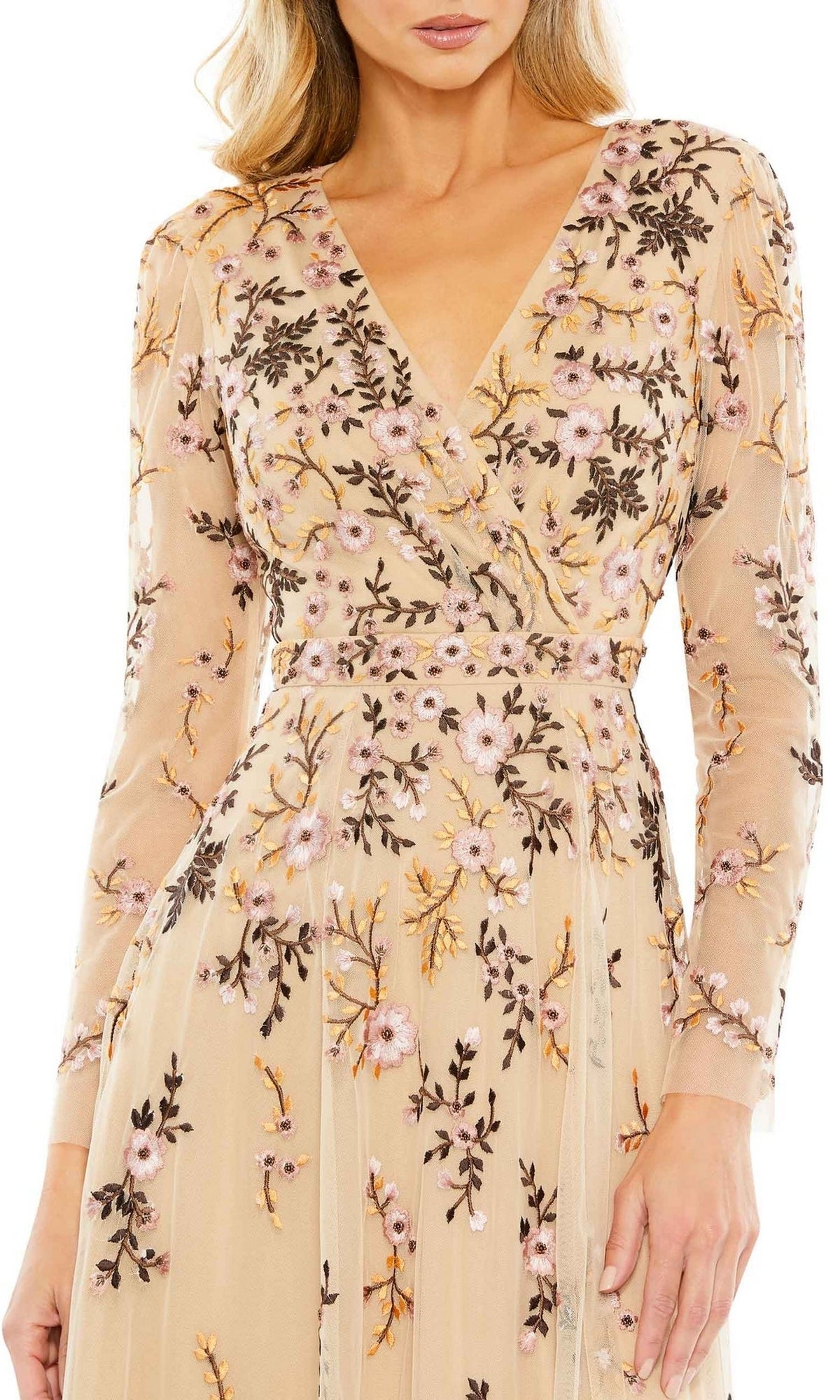 A woman wears the Mac Duggal Midi Floral Wedding Guest Dress in beige, featuring long sleeves, a fitted waist, a V-neckline, and pink, purple, and gold floral embroidery.