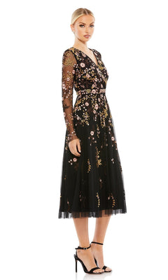 A woman in the Mac Duggal Midi Floral Wedding Guest Dress—black, long sleeve, with vibrant floral embroidery—paired with black high-heeled sandals, stands against a white background.