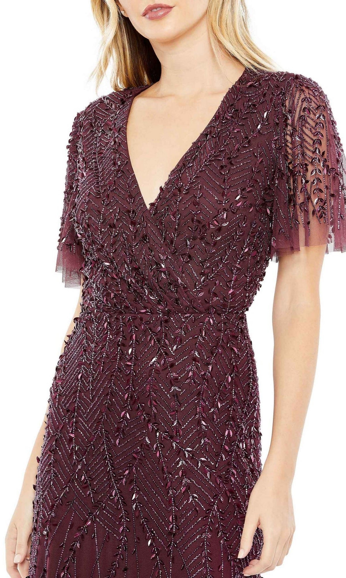 A woman wears the Mac Duggal 35109 Flutter-Sleeve Long Formal Dress in deep burgundy, featuring intricate bead and sequin leaf embellishments.