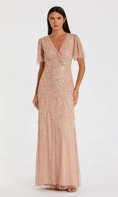 A woman wears the Mac Duggal 35109 Flutter-Sleeve Long Formal Dress in blush pink, featuring short flutter sleeves, a V-neckline, and intricate beaded embellishments, standing against a plain white background.