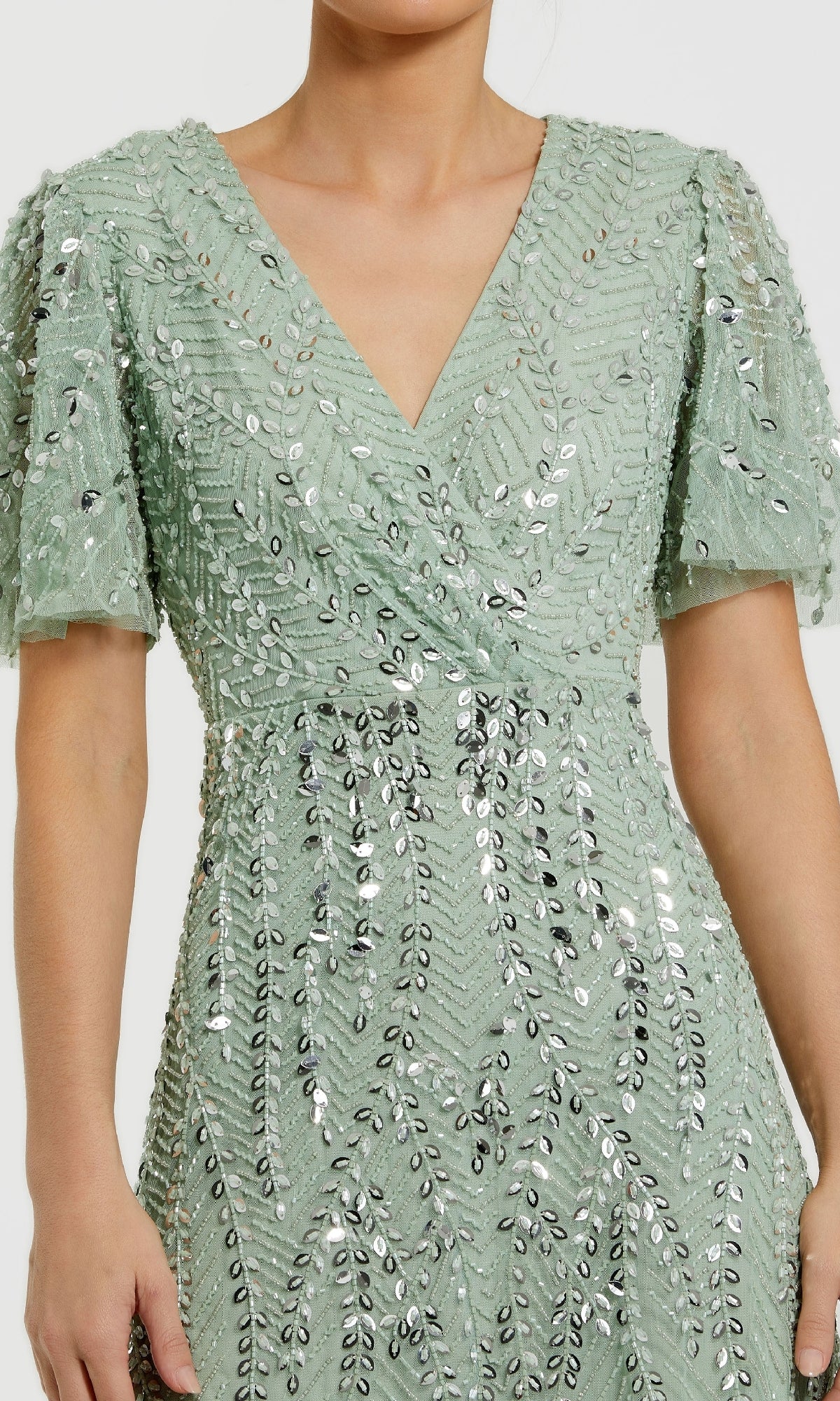 A person wearing the Mac Duggal 35109 Flutter-Sleeve Long Formal Dress in light green with a V-neckline and silver sequin leaf details, ideal for an elegant evening look.