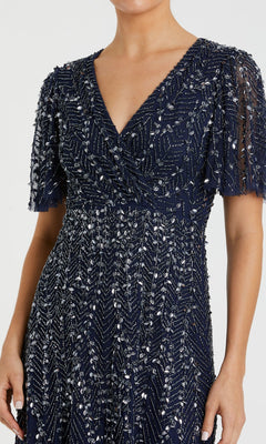 Someone wearing the Mac Duggal 35116 beaded midi semi-formal dress in navy blue, adorned with silver sequin and bead geometric embellishments.