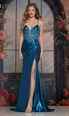 A woman wears the Colors Dress 3564, a long metallic prom dress with a shiny blue finish and thigh-high slit, standing before a floral and arched window backdrop.