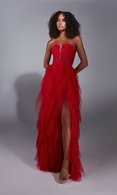 A woman poses in the A-Line Glitter Prom Dress: Aerie Couture 356, showcasing a strapless design with a sheer bodice, ruffled A-line skirt, sparkling details, and a high front slit against a plain gray background.