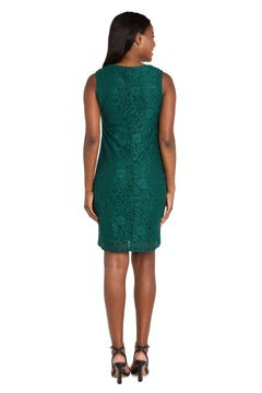 A woman stands facing away, wearing the R&M Richards 3594 short semi-formal jacket dress in green with black high-heeled sandals—ideal for a semi-formal event.