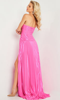 A woman in profile wears the Jovani 36461, a strapless long pleated prom dress with a shiny pink finish and high slit, styled with nude heels and drop earrings against a plain background.
