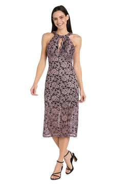 A woman smiles while wearing the R&M Richards 3648 mauve knee-length party dress with a high neck and keyhole detail, paired with black strappy heels.